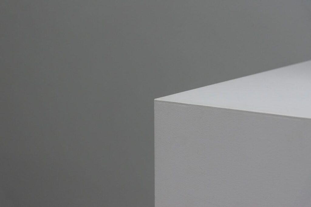 A minimalist image showcasing a sleek geometric shape with neutral grey and white tones.