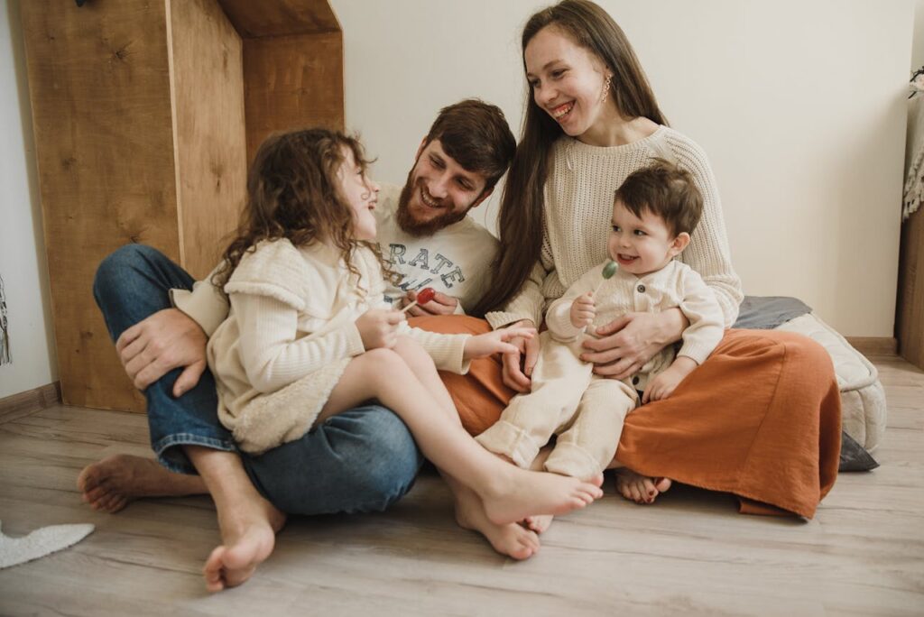 Smiling family of four sitting on the living room floor, enjoying quality time together.
