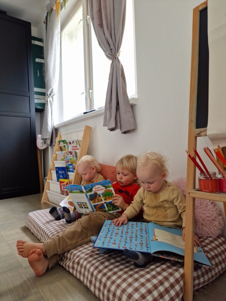 Kolm last loevad koos raamatuid lugemisnurgas